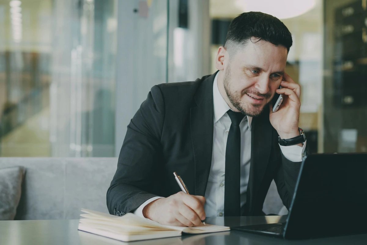 Comercial atendiendo una llamada con un cliente y anotando señales de compra