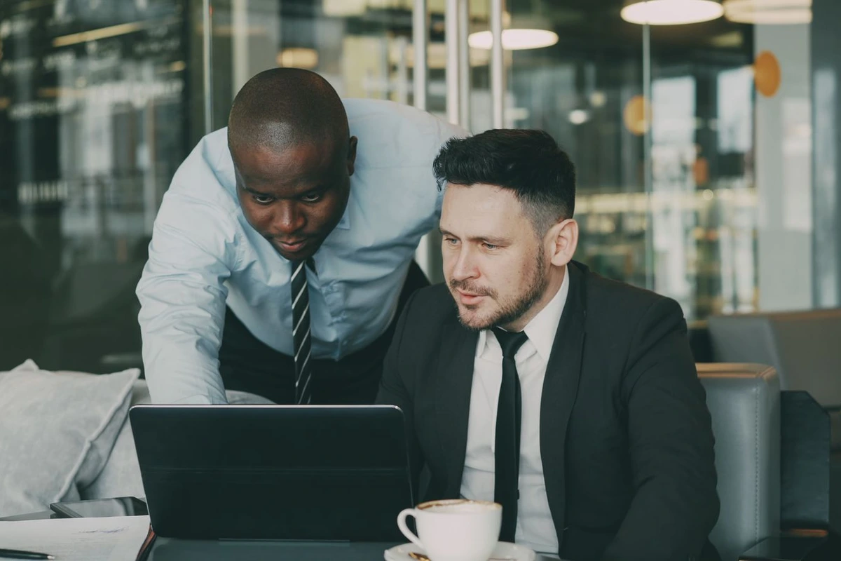 Dos comerciales revisando juntos los datos de un cliente en la pantalla de un portátil