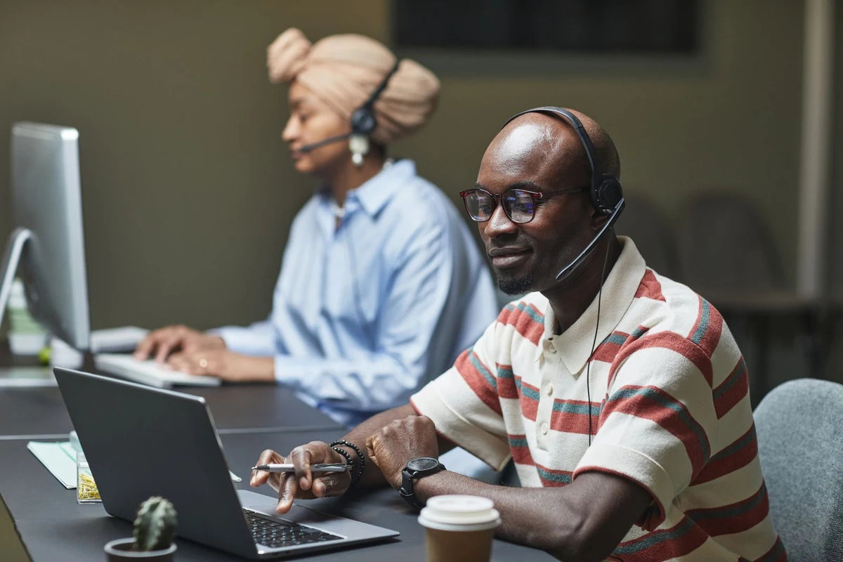 Equipo de ventas internas trabajando con ordenadores y auriculares en la oficina