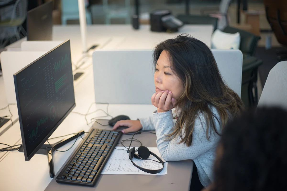 Profesional concentrada analizando datos en el monitor de su puesto de oficina