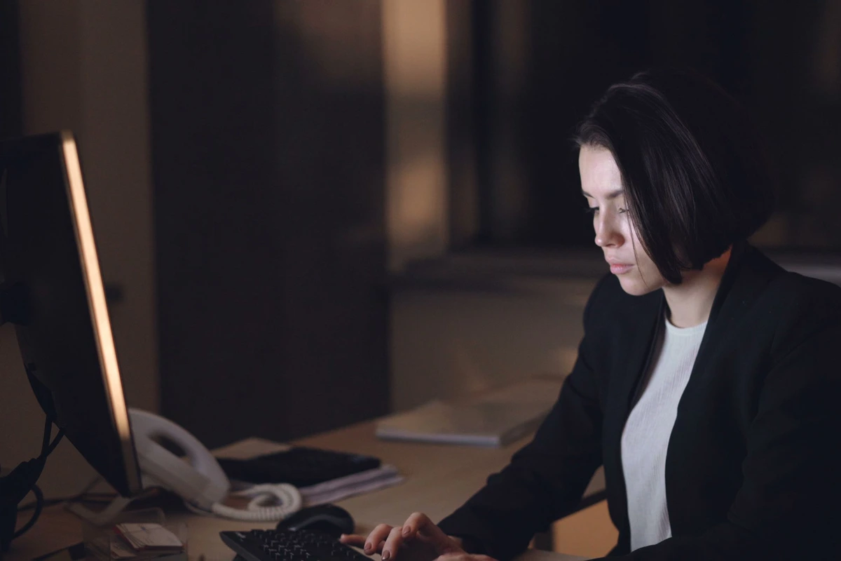 Profesional trabajando frente a un monitor de escritorio en una oficina en penumbra